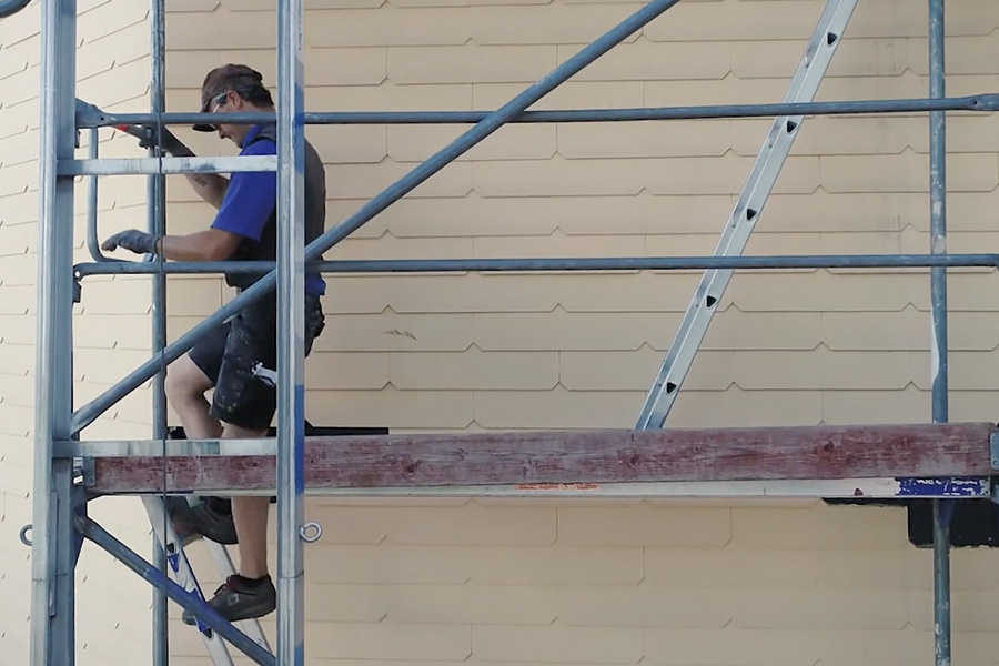 Dachdecker steigt ein Gerüst herunter.